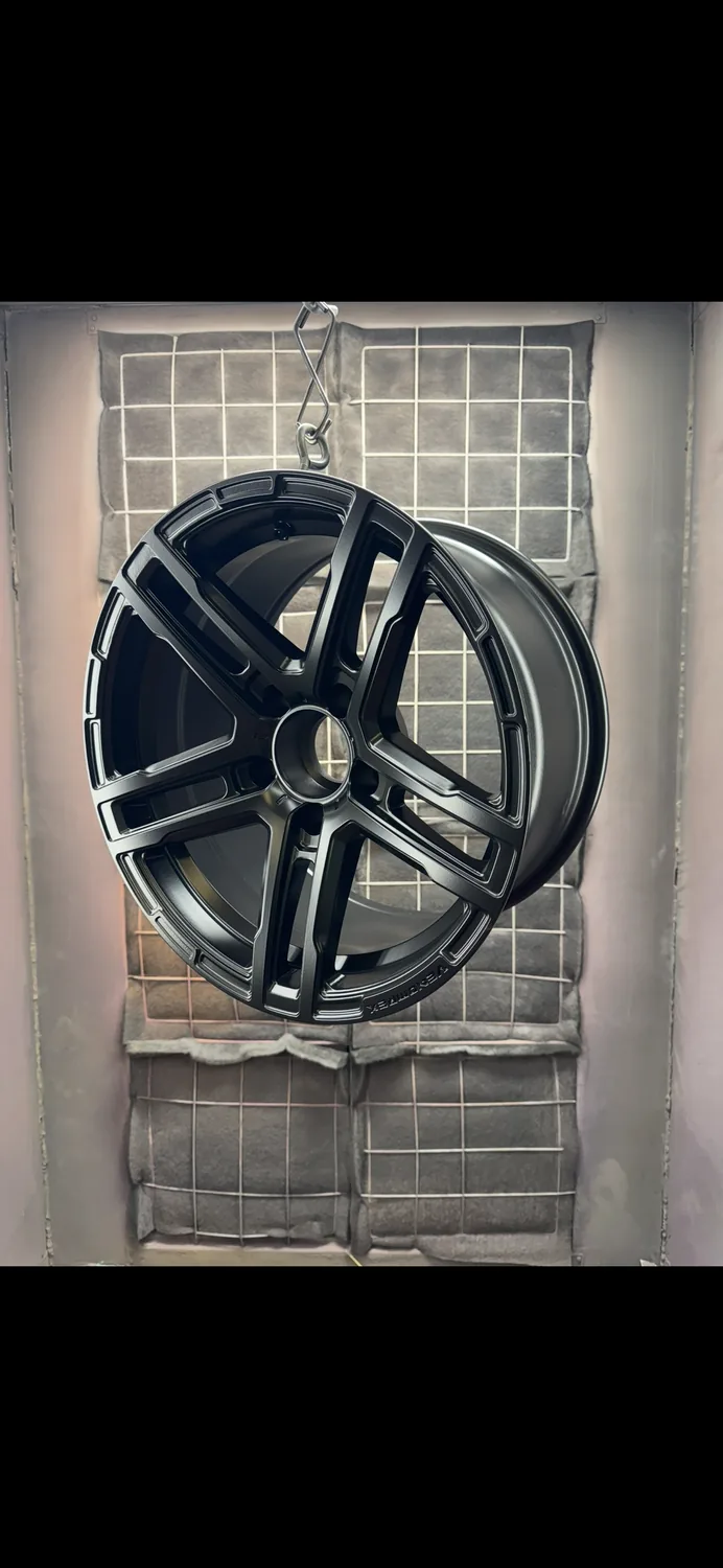 A satin black powder coated wheel hanging in the workshop